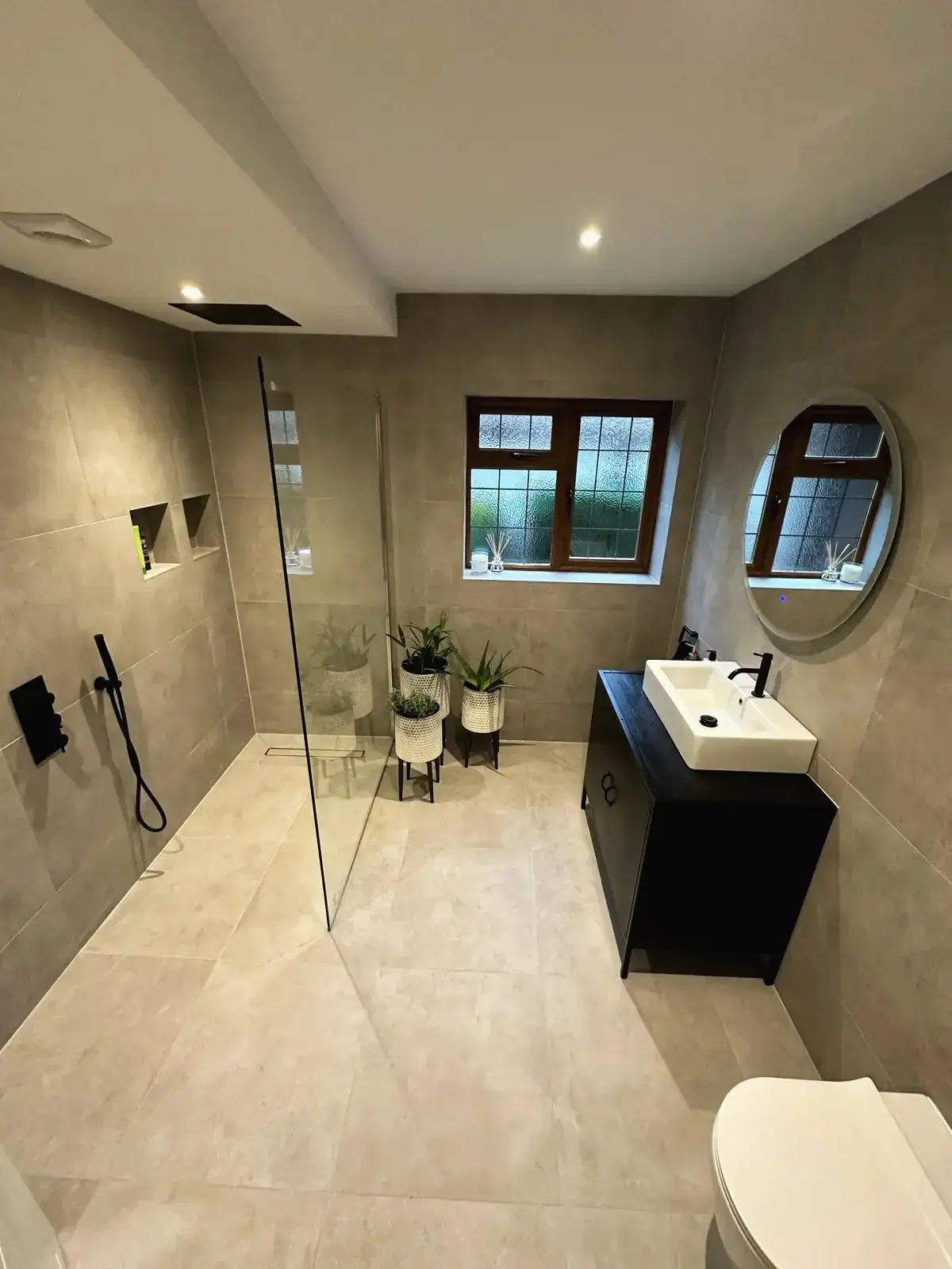 Bathroom renovation with a walk-in shower, large-format tiles and a black vanity unit