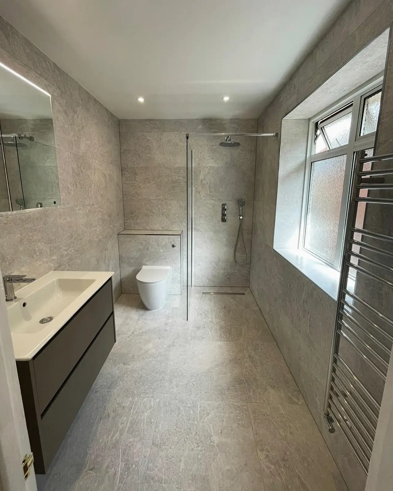 Renovated bathroom with a walk-in shower, wall-hung vanity and towel radiator