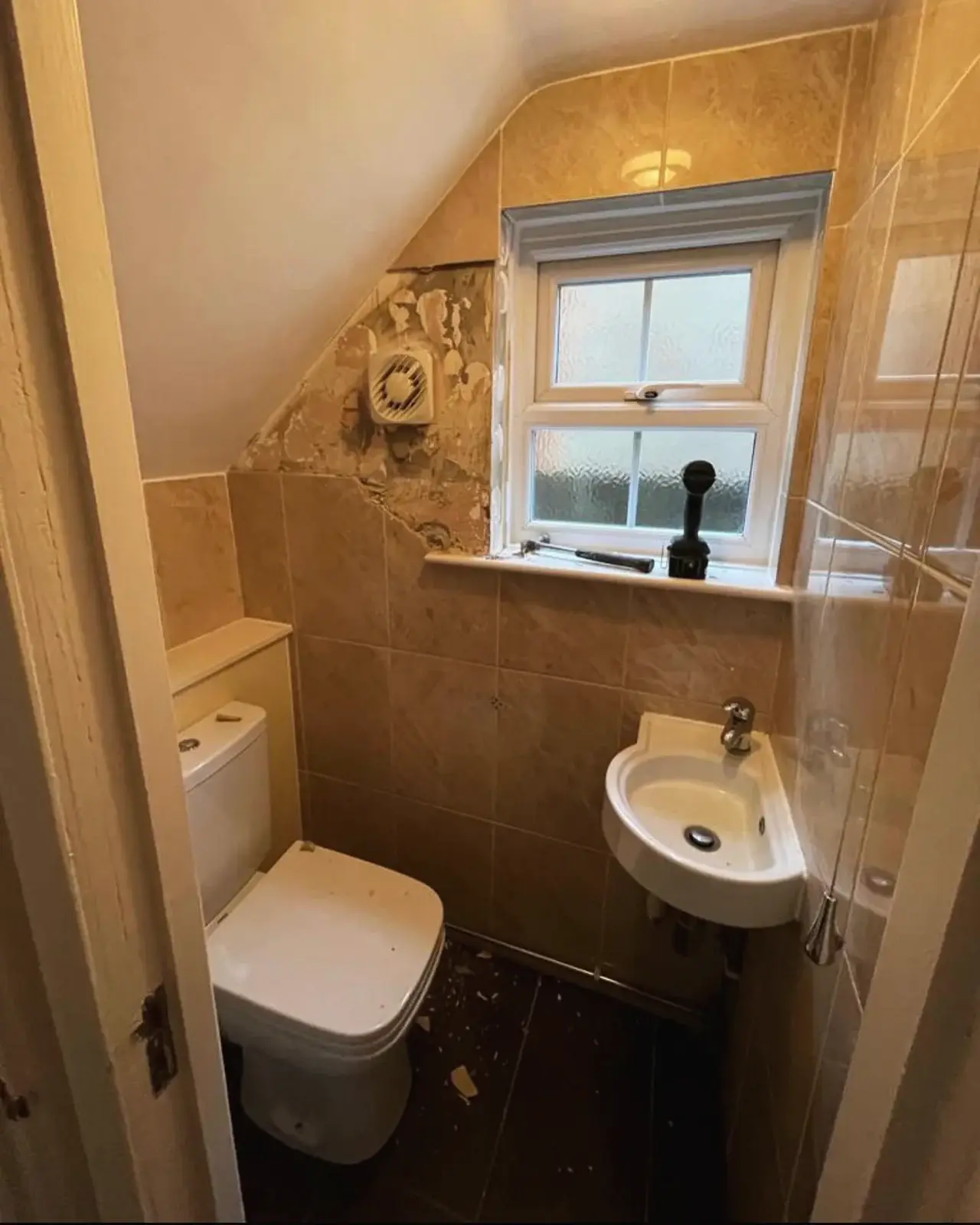 Cloakroom before renovation, with dated tiles and a corner basin