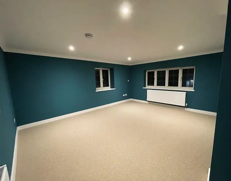 The same garage converted into a carpeted, decorated room with new windows