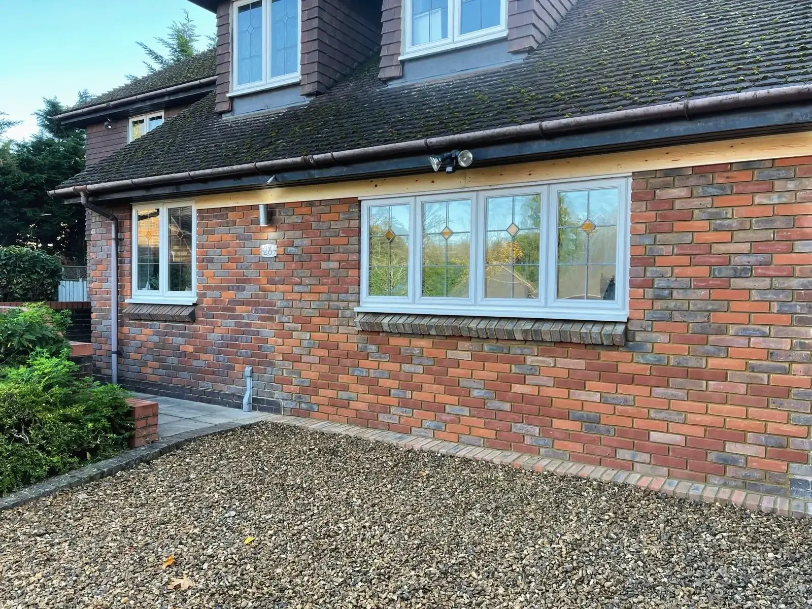 Brick house frontage after renovation, with new windows and exterior lighting