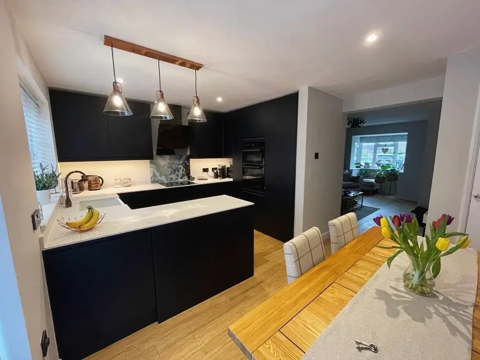 Navy kitchen with an island, pendant lights and a dining table