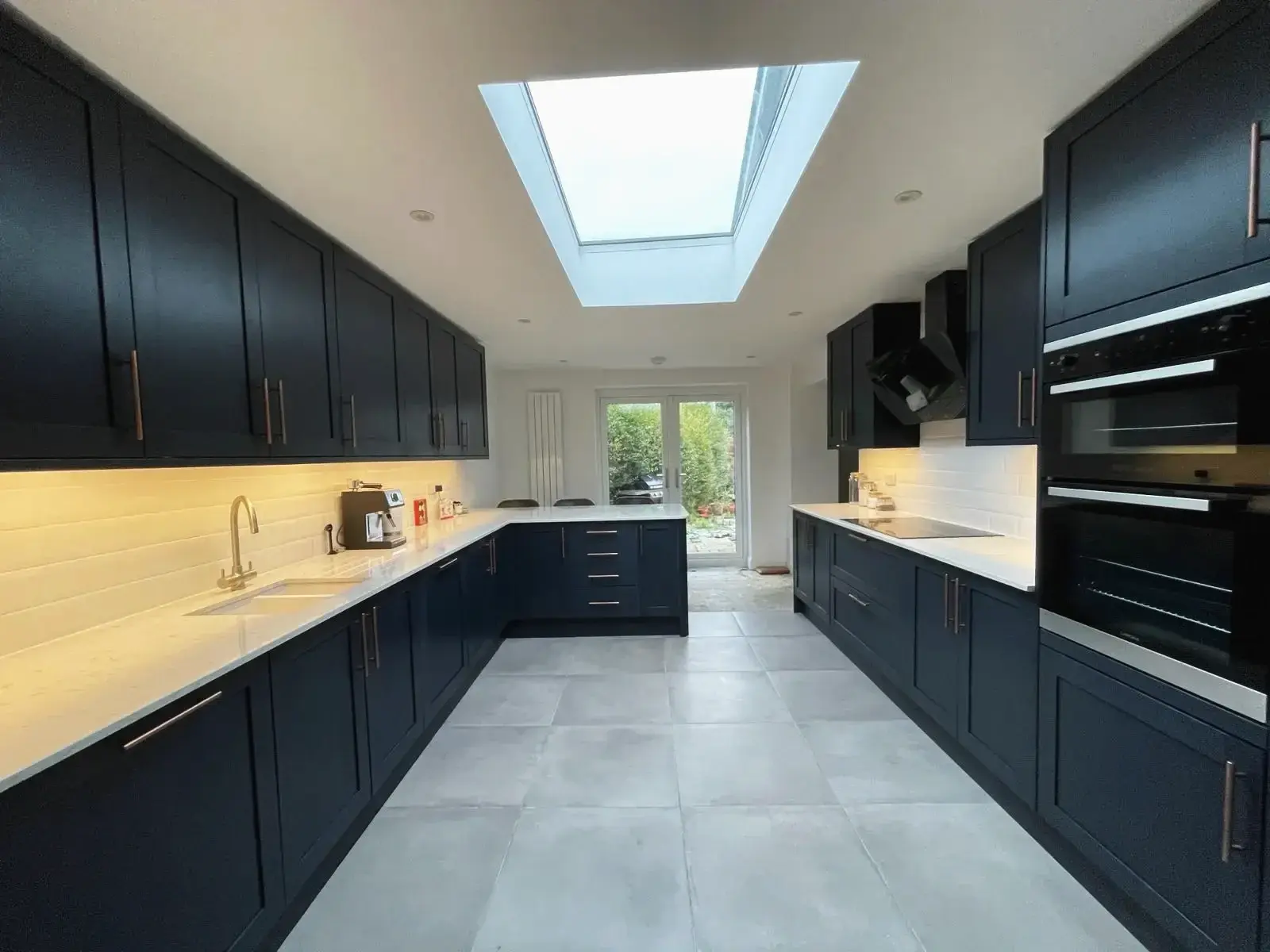 Navy kitchen renovation with a roof lantern, quartz worktops and integrated ovens