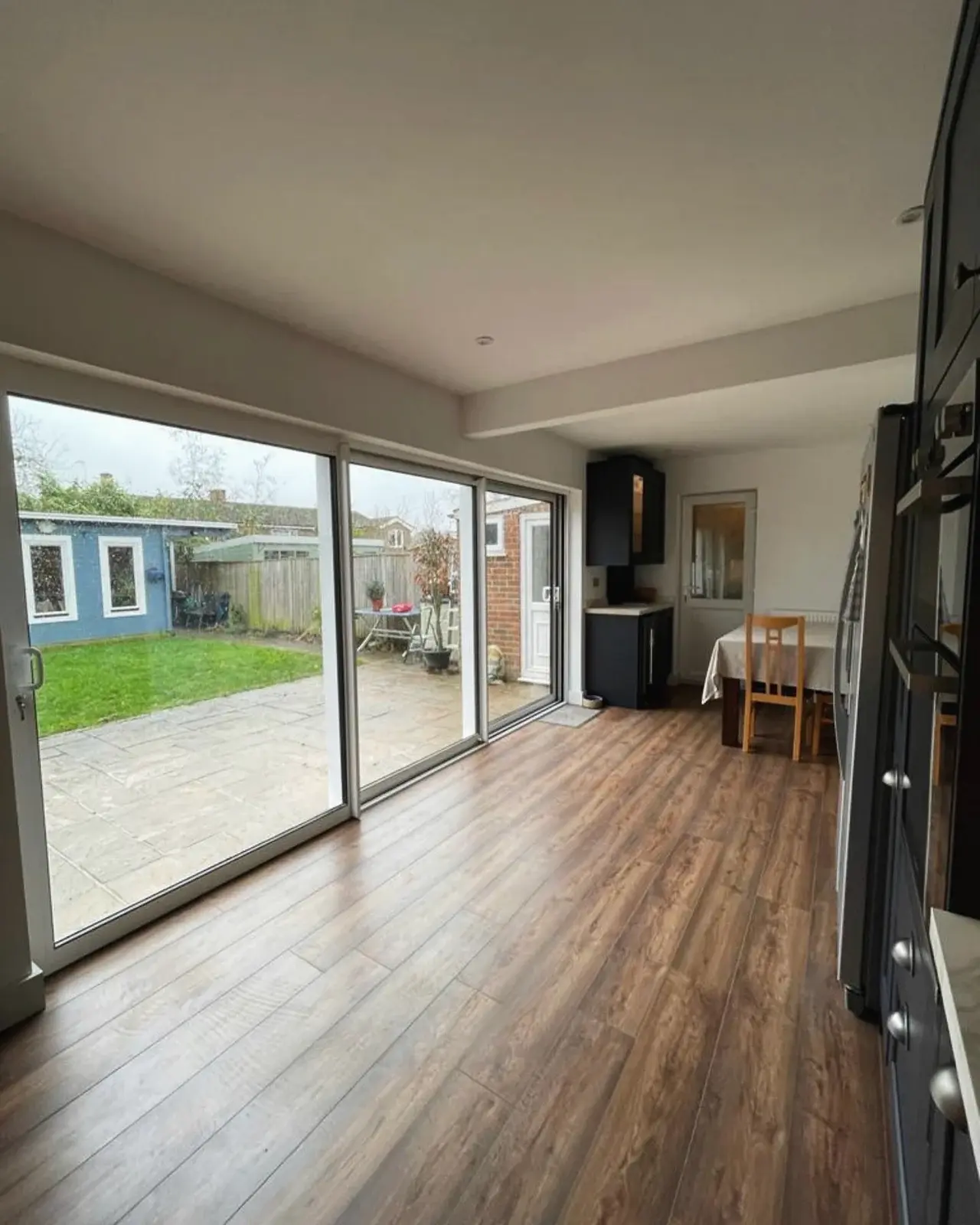 Open-plan room with new wide sliding doors and wood-effect flooring